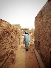 Full length rear view of man walking against wall