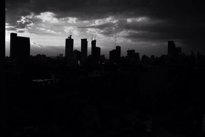 Skyscrapers in city against cloudy sky