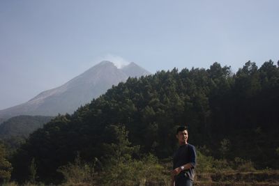 Portrait of young woman standing on mountain against sky