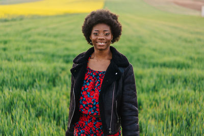 Portrait of smiling young woman standing on field