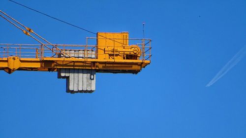 Low angle view of crane against clear blue sky