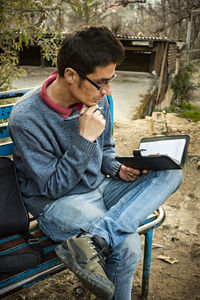 Man reading book while relaxing on bench at park