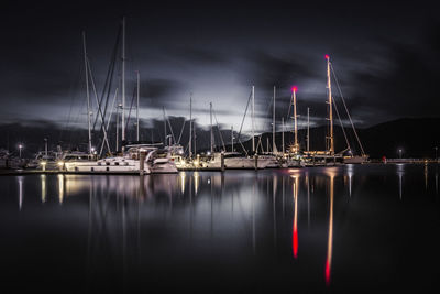 Sailboats moored at harbor against sky at night