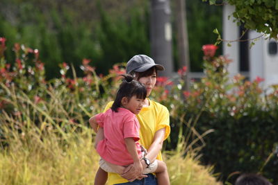 Mother carrying daughter while standing on field