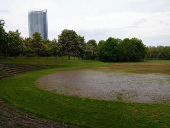 Scenic view of park by buildings against sky