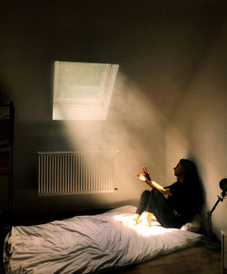 Woman sitting on bed at home