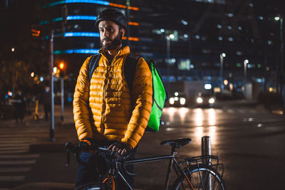 Man riding bicycle on road in city at night