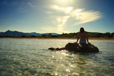 Young woman in water against sky