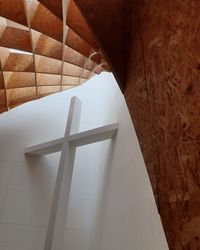 Low angle view of cross on wall in building