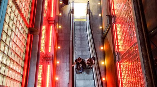 Rear view of man standing on illuminated staircase in building