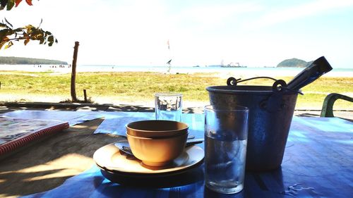 Coffee cup on table by sea against sky