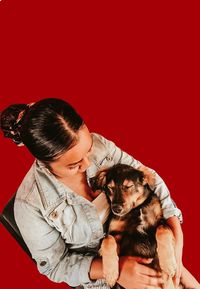Woman with dog against red background