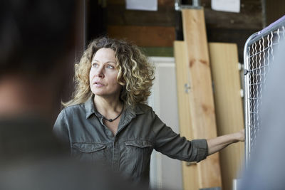 Mature female volunteer with blond curly hair standing in front of coworker at warehouse