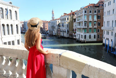 Woman standing by canal against buildings in city