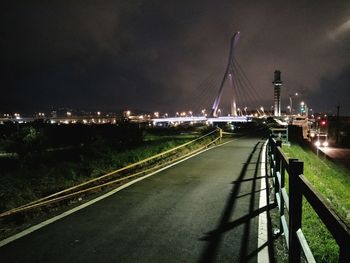 Illuminated bridge over city against sky at night