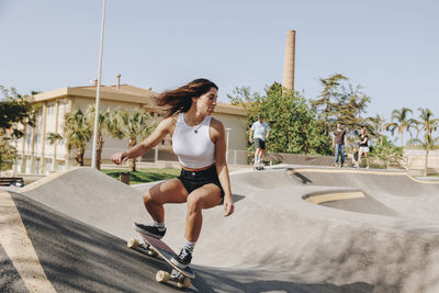 Young woman skateboarding on sports ramp at skatepark