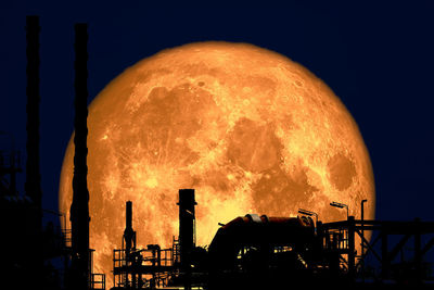 Silhouette of factory against sky at night