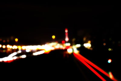 Defocused image of illuminated city against sky at night