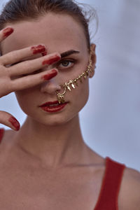 Close-up portrait of woman wearing nose ring against blue background