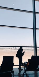 Silhouette of man standing on airport against sky