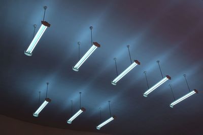 Low angle view of illuminated fluorescent lights hanging from ceiling