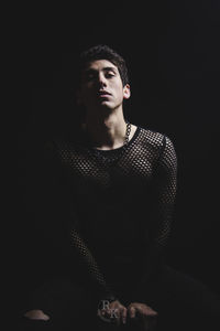 Portrait of young man standing against black background