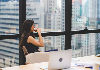 Woman using phone while sitting on table