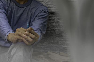 Midsection of man holding while sitting at home