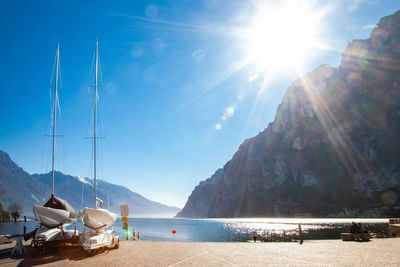 Sailboats moored on sea against sky on sunny day