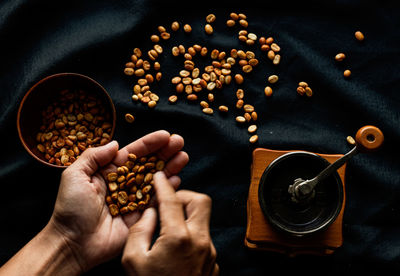High angle view of hands holding coffee beans on table