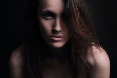 Portrait of naked young woman against black background