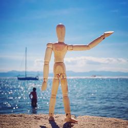 Rear view of people standing at beach against sky