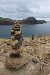 Stack of rocks by sea against sky