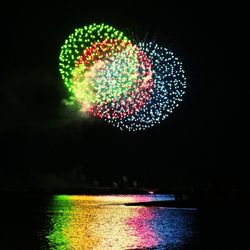 Illuminated firework display over water at night