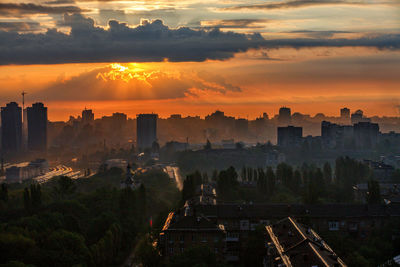 The sun's rays break through the thick rain clouds and the rain wall at dawn over the silhouette.