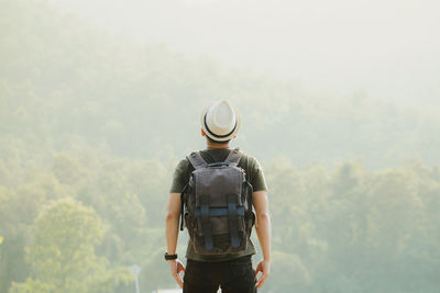 Rear view of man standing against trees