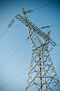 Low angle view of electricity pylon against clear blue sky