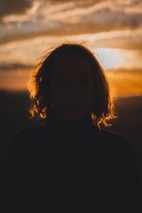 Portrait of a young woman standing against sky during sunset