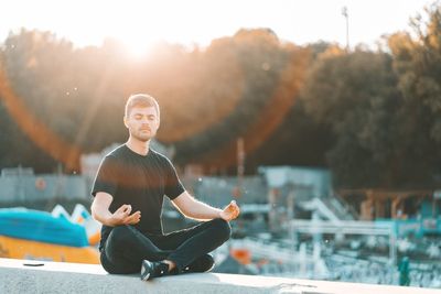 Full length of young man sitting outdoors