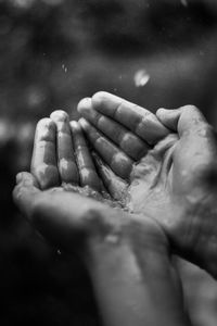 Close-up of water drop on cupped hands in rainy season