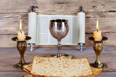 Matzo with drink and candles on wooden table against wall