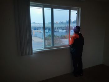 Rear view of man looking through window