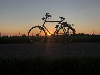 Bicycle on field against sky during sunset