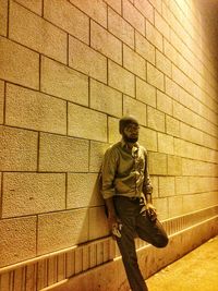 Young man standing against brick wall