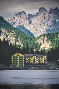 Scenic view of river by houses and mountains against sky