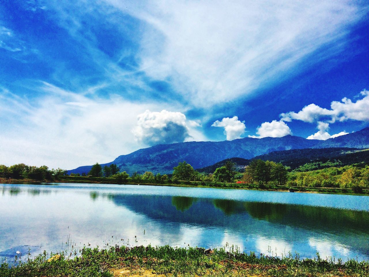 SCENIC VIEW OF LAKE BY MOUNTAINS AGAINST BLUE SKY