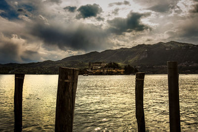 Wooden posts in lake against mountains