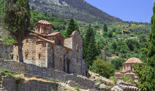 Old building by trees and mountains against sky