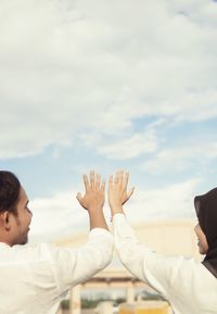 Side view of man with arms raised against sky