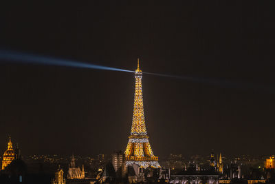 Illuminated tower in city against sky at night
